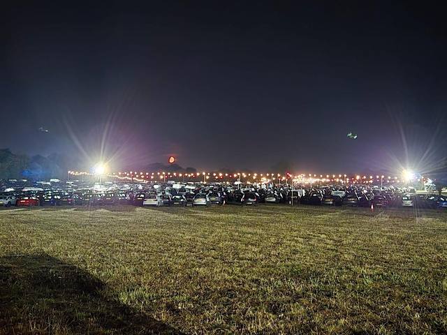 Festival car park at night, lit by tower lights along the boundary