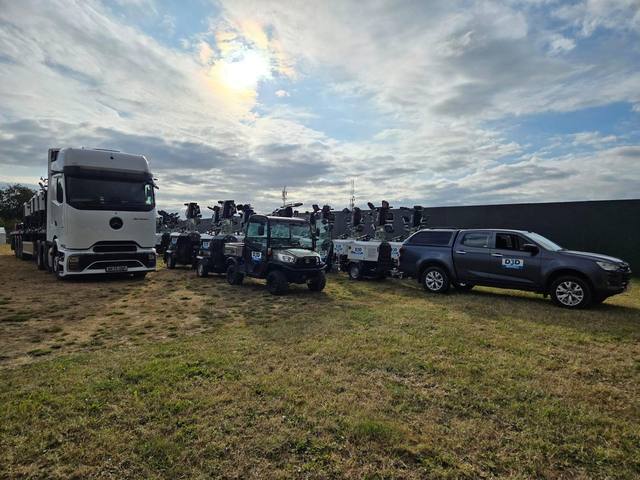 Delivery vehicles and tower lights arriving at an event site
