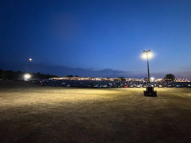 Event car park lit by a single tower light at dusk