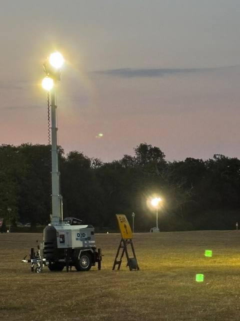 Tower lights coming on at dusk across an event site